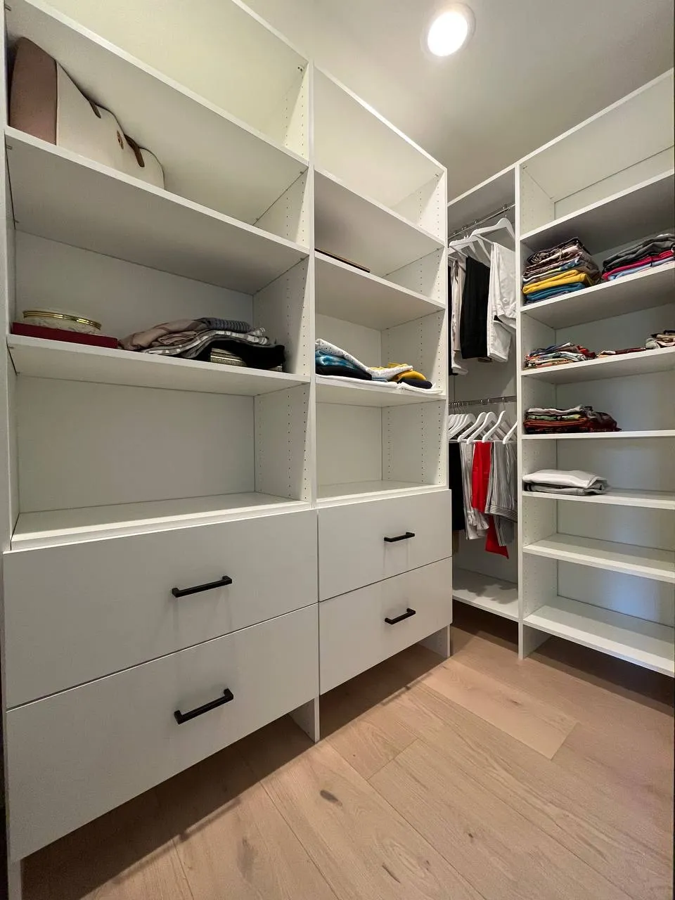 Custom white walk-in closet with drawers and shelving in Encino