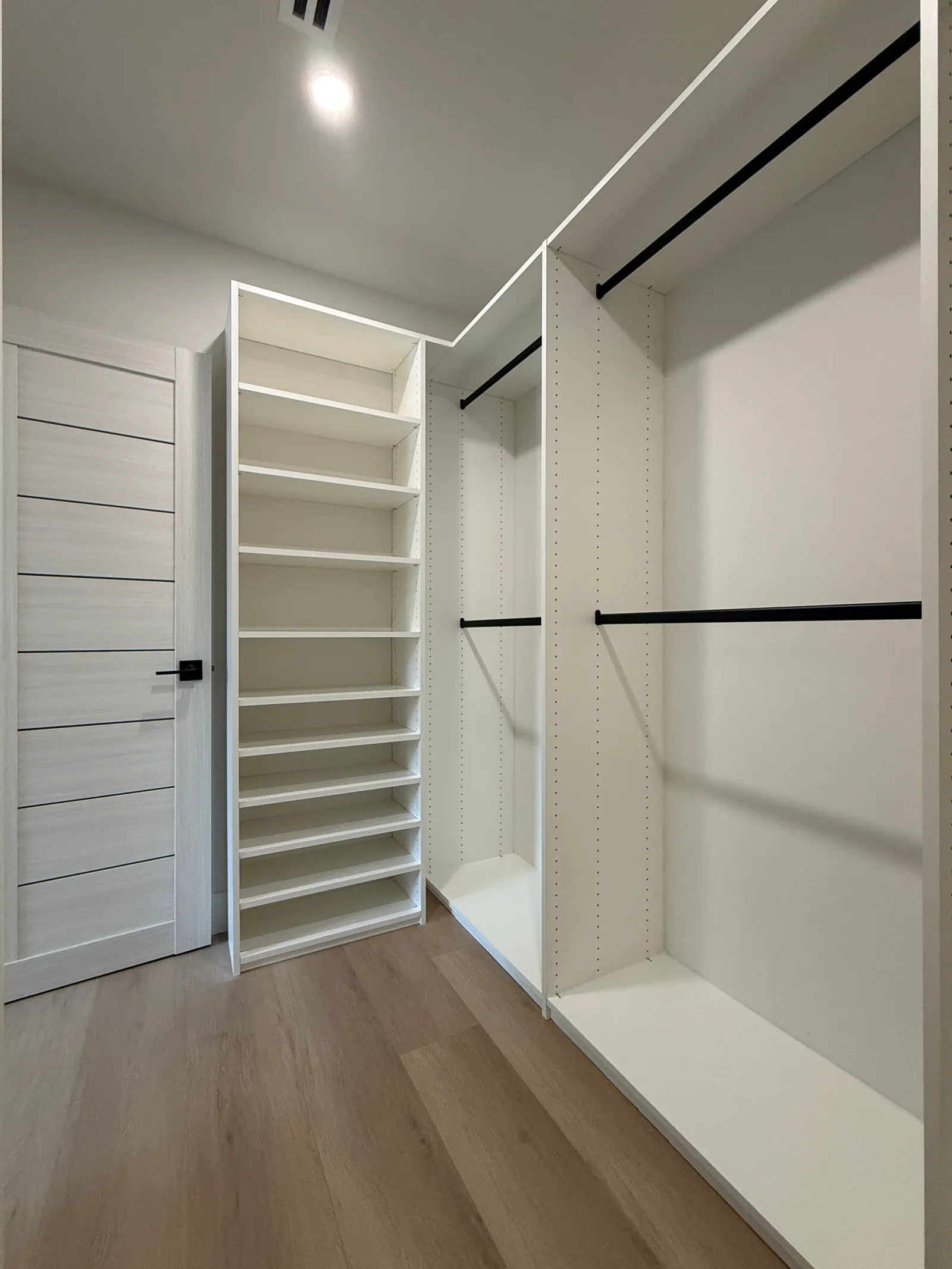 White melamine walk-in closet with open shelving and black hanging rods in North Hollywood
