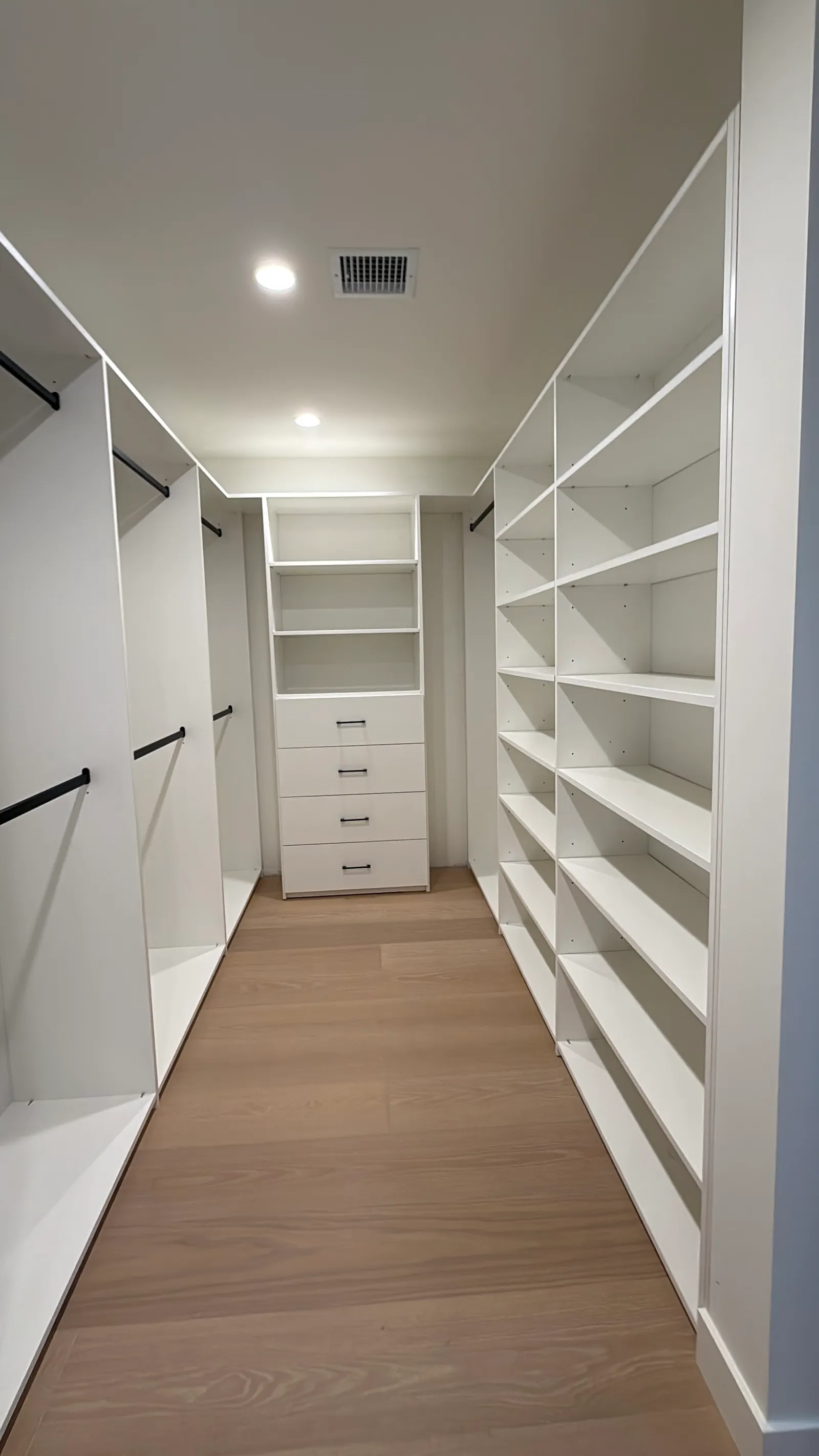 Custom closet storage with black hanging rods, shelves, and built-in drawers