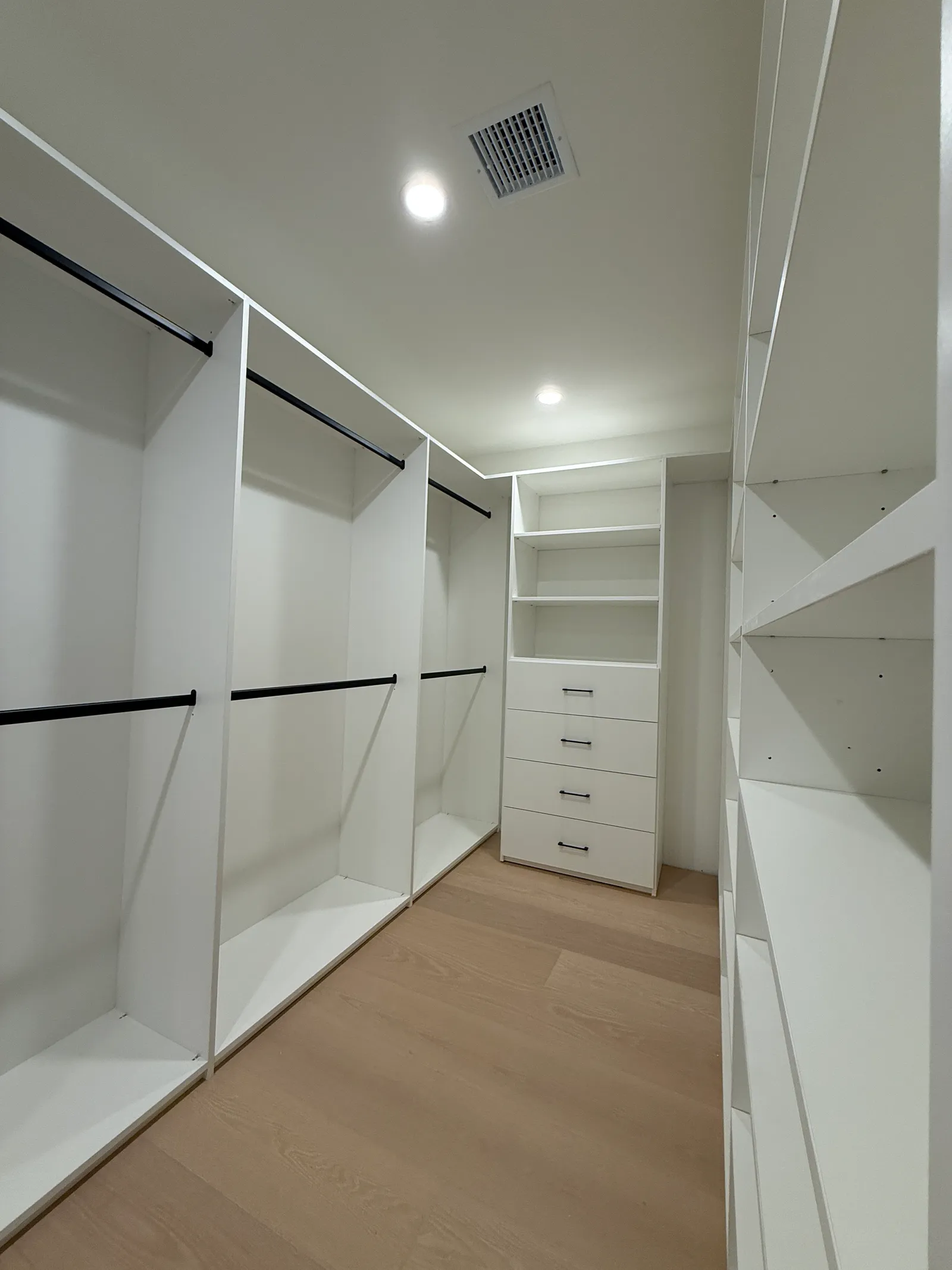 White walk-in closet with double hanging sections and adjustable shelving