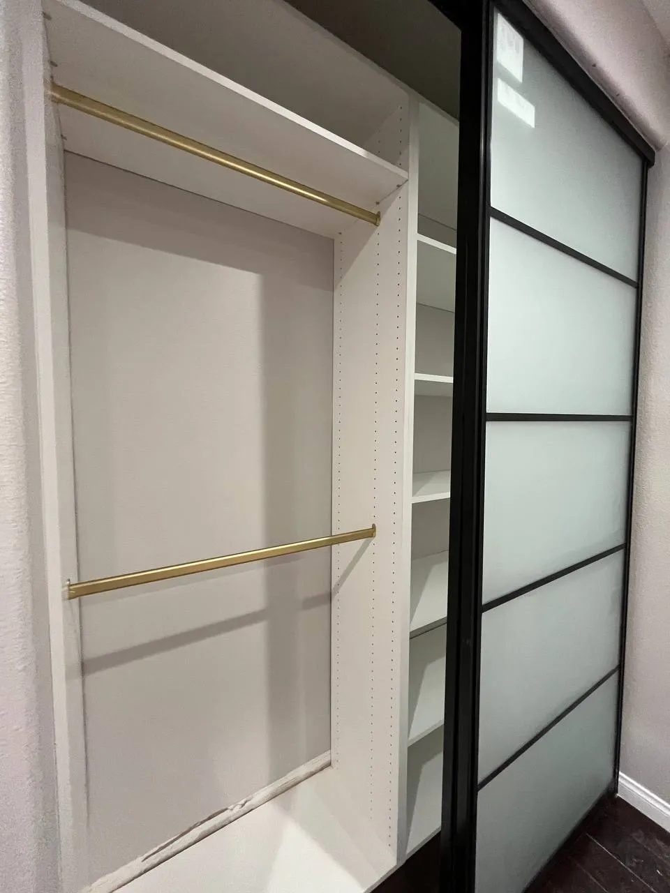 Reach-in closet hanging section with white melamine cabinetry and sliding door frame