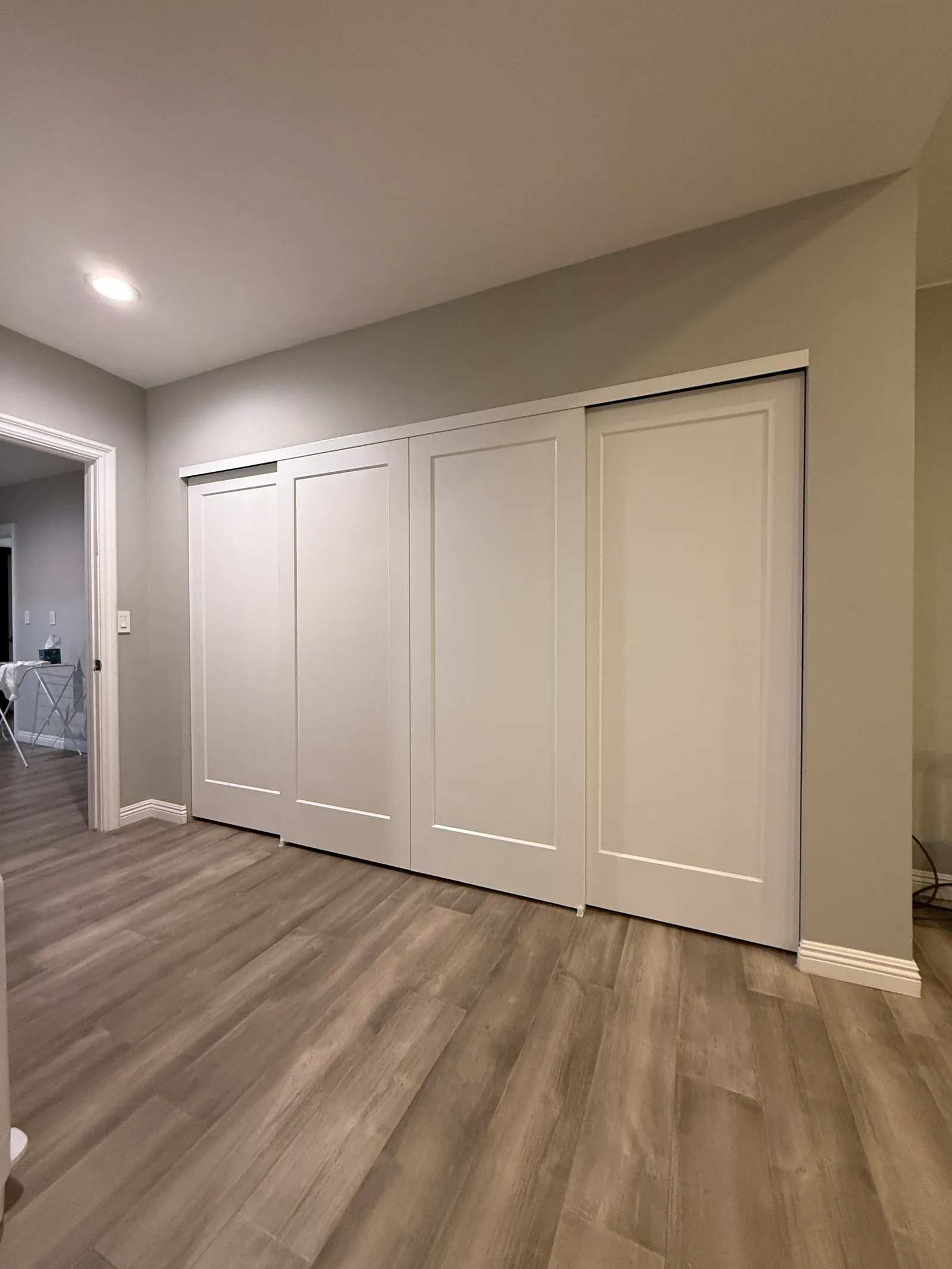Four white Shaker-style sliding closet doors along a wall in a Northridge home
