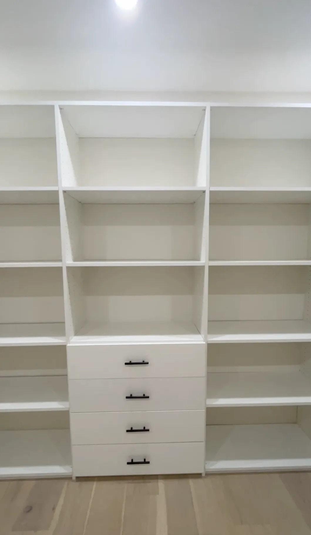 White melamine walk-in closet with central drawers and open shelving in La Crescenta