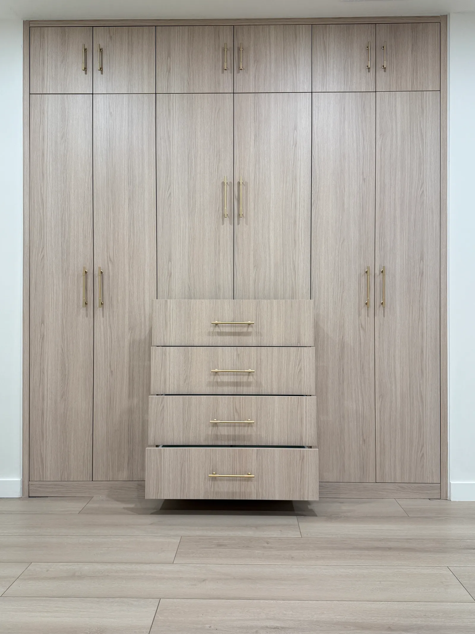 Built-in wood-look wardrobe with central drawers and upper storage cabinets