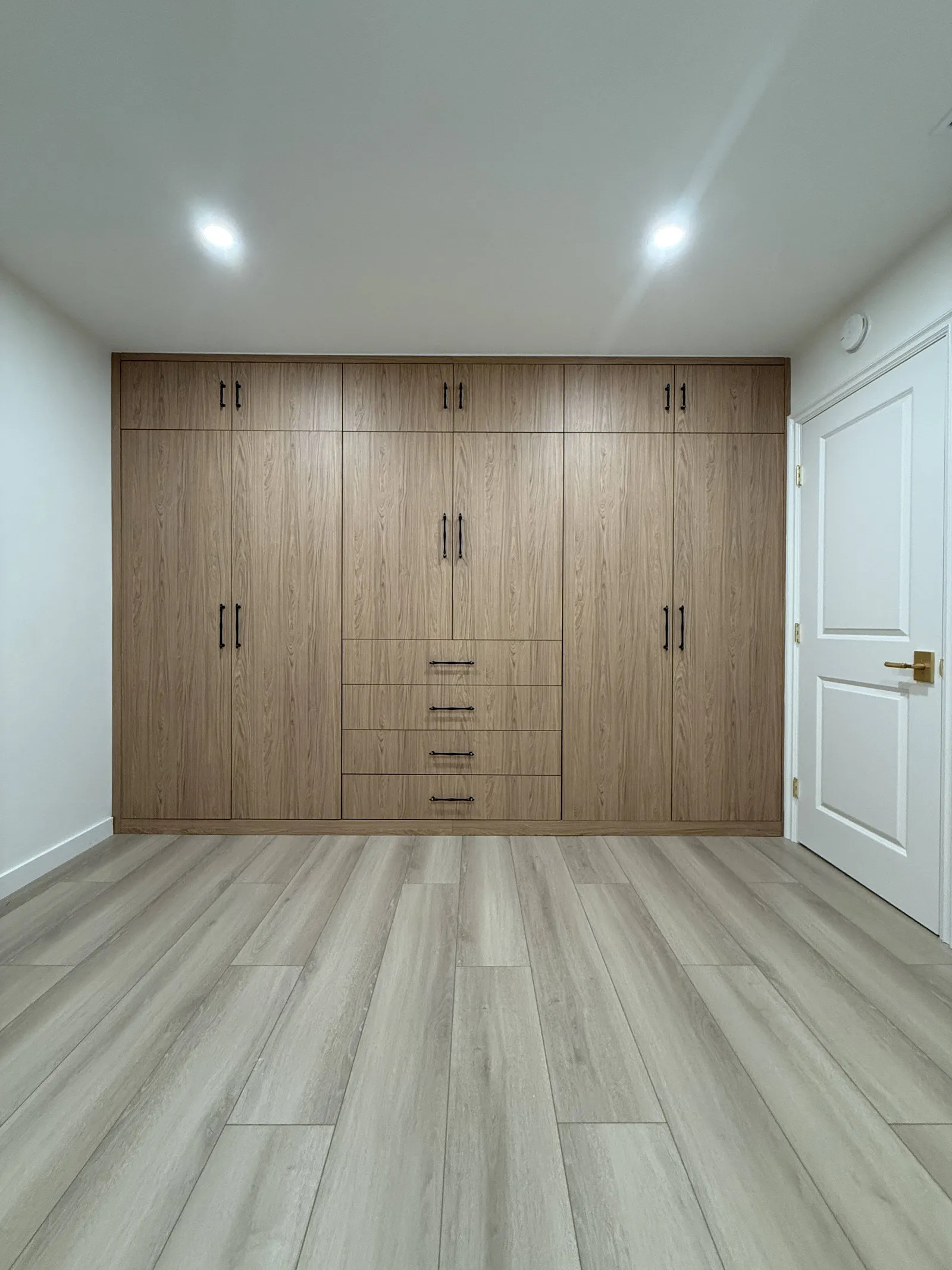 Custom bedroom wardrobe wall with wood-look cabinetry in Tujunga