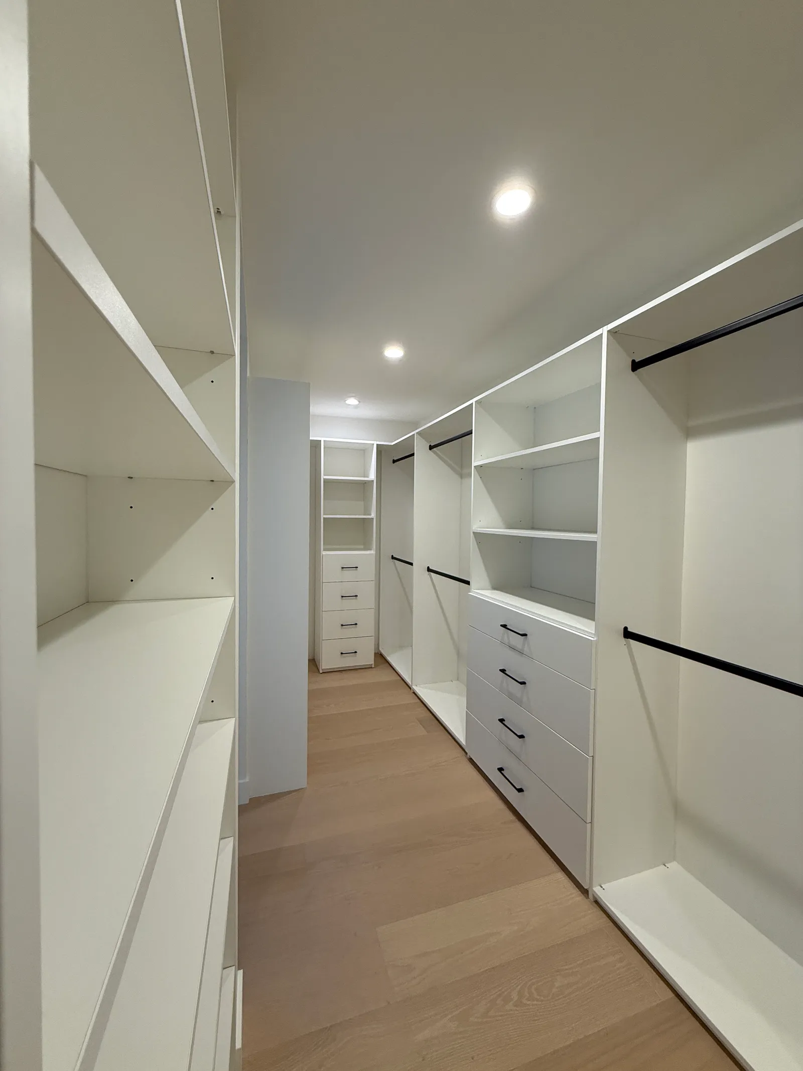 Custom white walk-in closet with shelving, drawers, and black hanging rods in Sun Valley