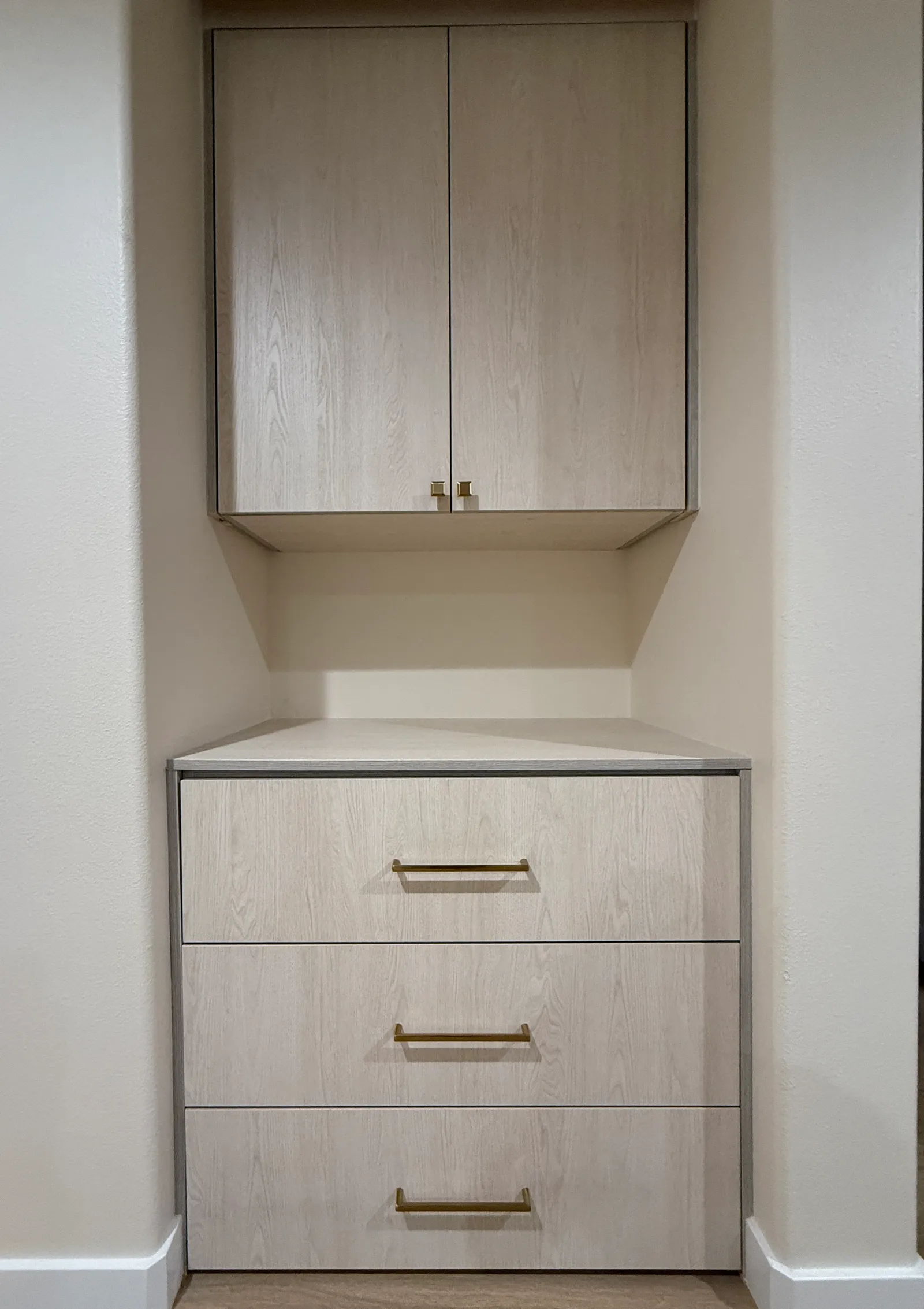 Compact custom wall unit in Sun Valley with wood-look melamine cabinetry, upper enclosed storage, and built-in drawers.