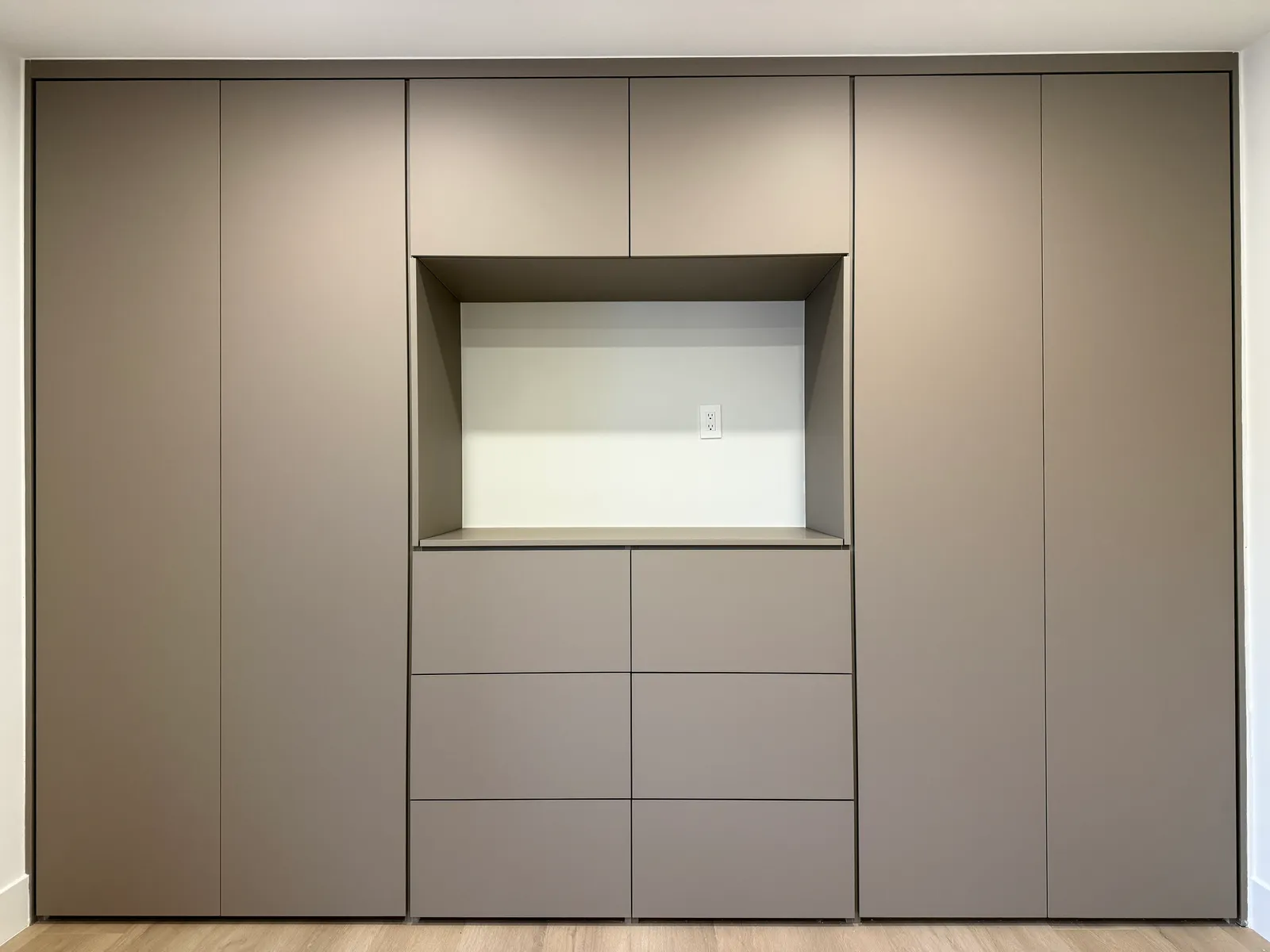 Custom wall unit with central niche and handle-free storage doors