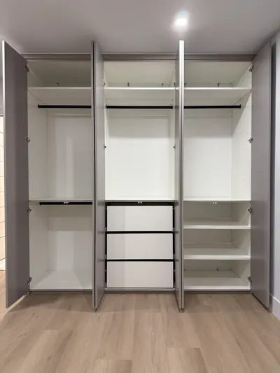 Custom wardrobe interior with central drawers, shelves, and hanging storage